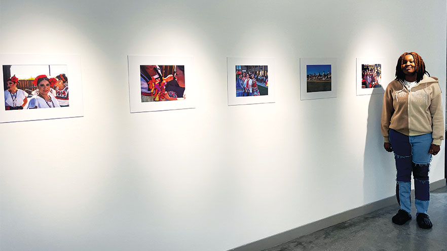 Asaya Johnson standing next to their art in a gallery.