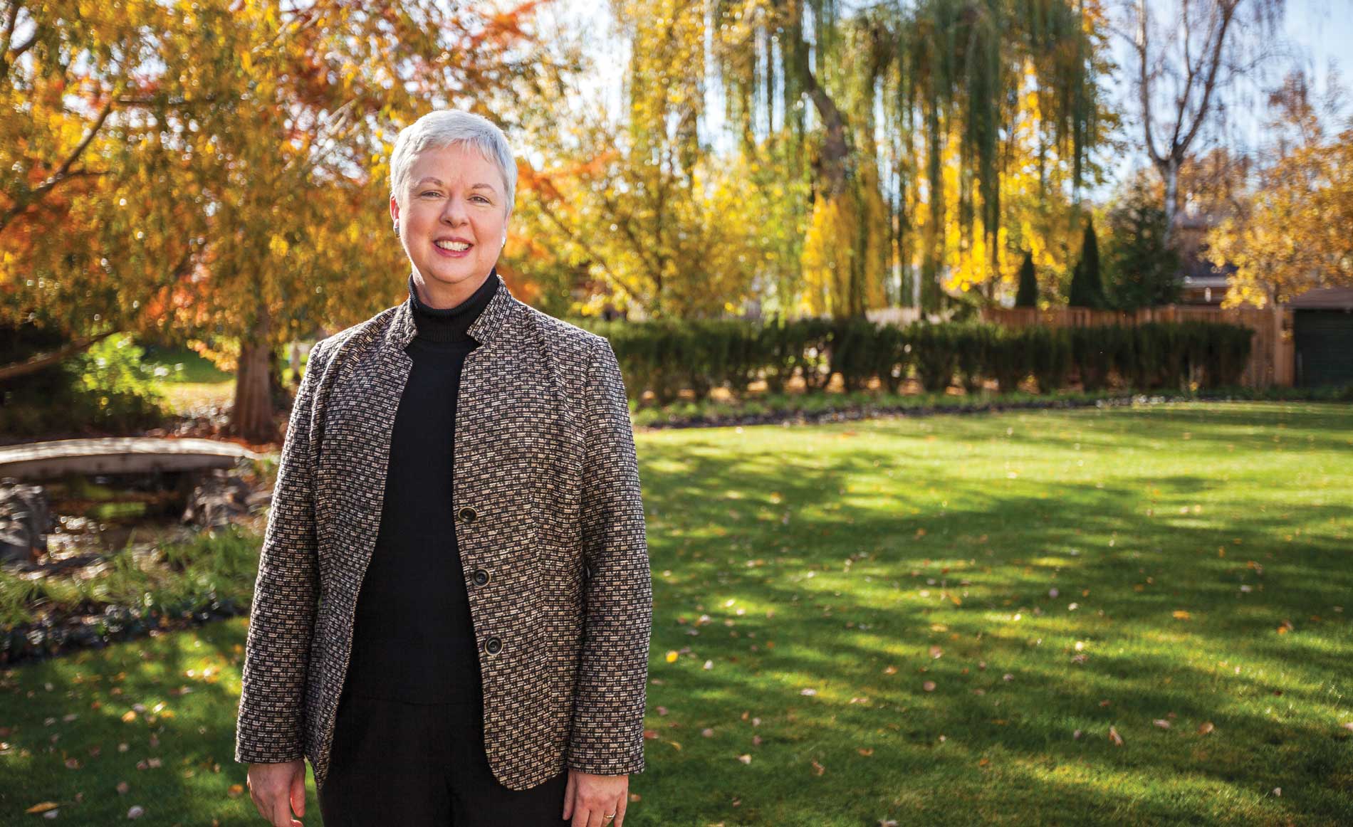 Whitman College president Kathy Murray standing outside with fall colors in the background.