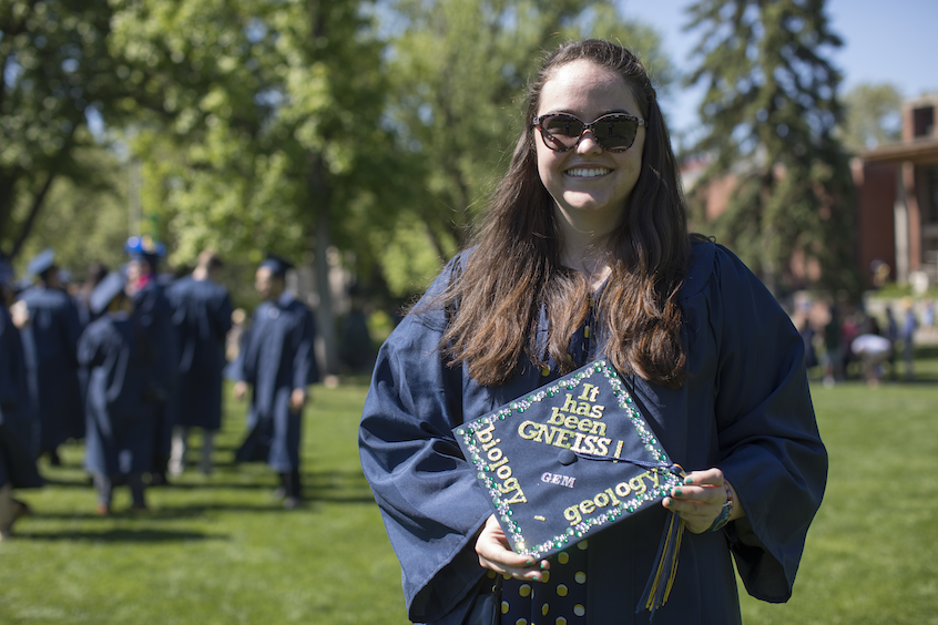 Gabby McGann, biology and geology major, with her Commencement cap decorated to say "It has been GNEISS!"