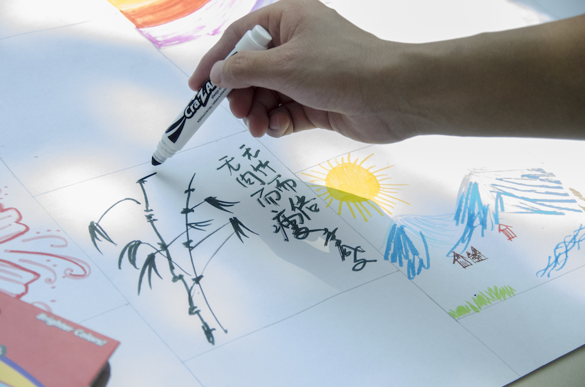 Chinese Language Assistant Andy Li draws at the Fine Arts House table.
