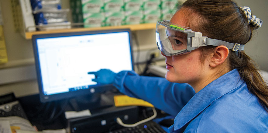 A student researcher points at a computer screen.