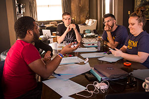 Debate students sit around a table practicing.