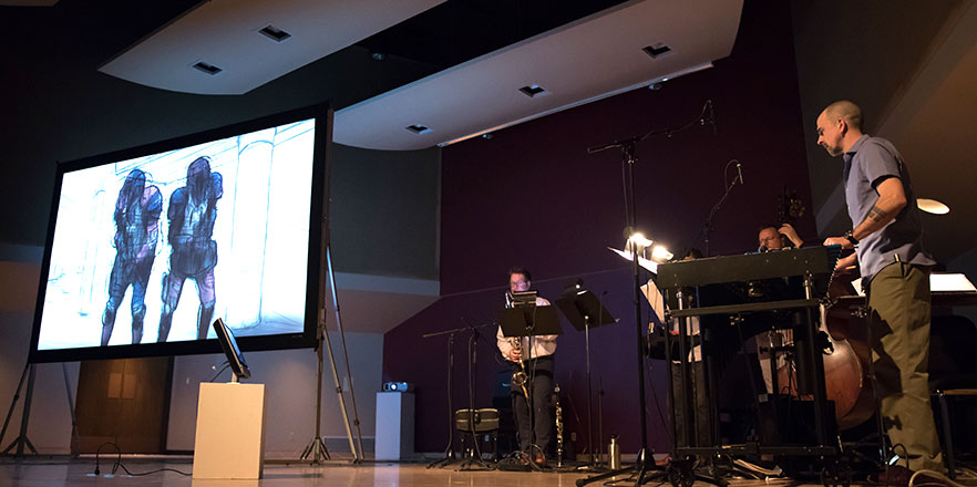 The chamber music group TORCH performs on stage as an animated art video plays near them.