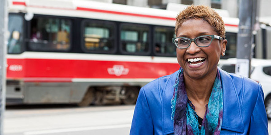 Paula Boggs smiles in front of a transit bus.