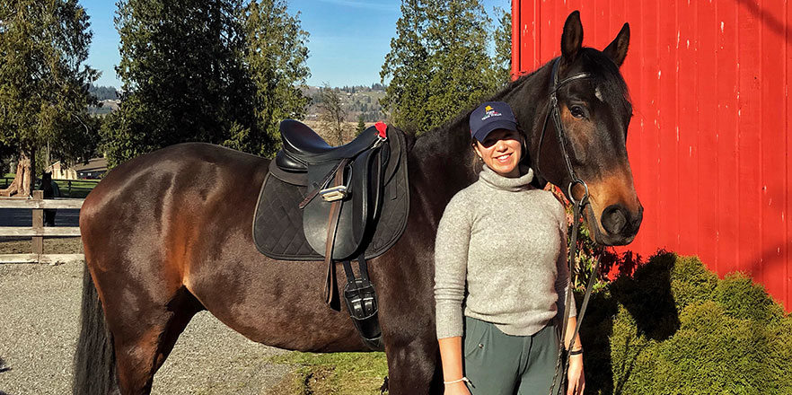 Cello Lockwood stands with a horse near a barn.