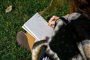 A student sketches a tree in a notebook.