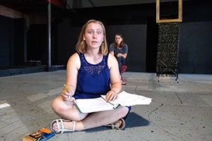 A student works on a play on stage.