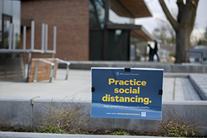 A sign in front of the dining hall reminds students to practice social distancing.