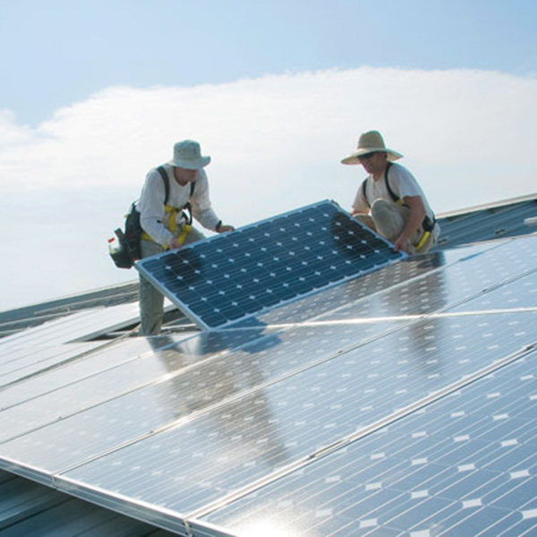 Two Whitman staff installing solar panels on roof.