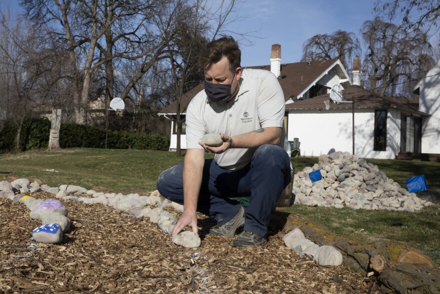 Interfaith Chaplain Adam Kirtley kneels by the labyrinth as he places a stone