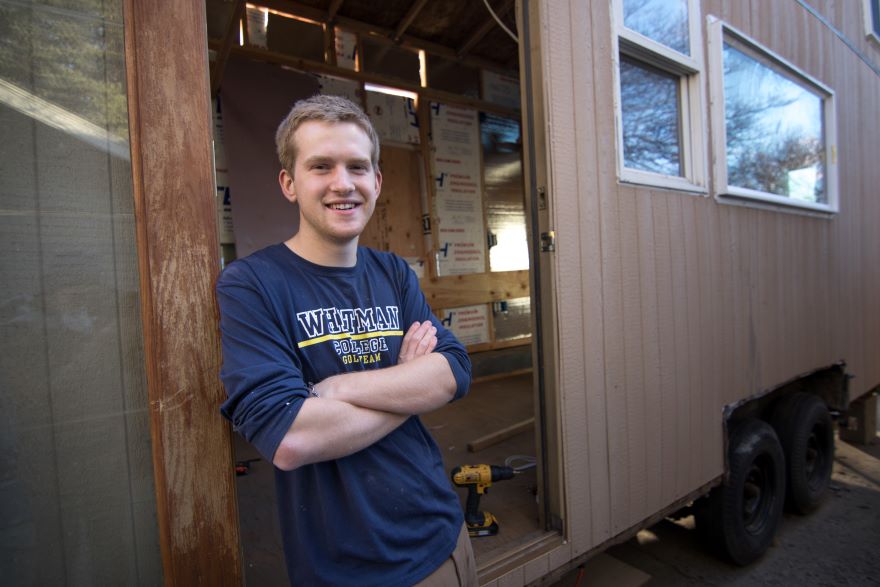 Preskenis smiles in the doorway of the tiny house