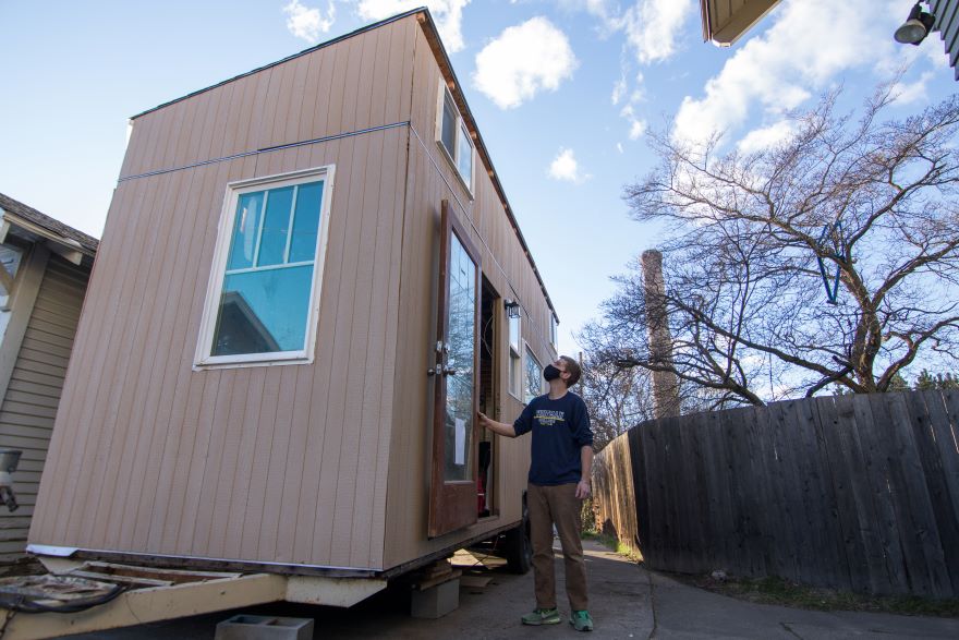 Preskenis stands outside the tiny house, the front of the house is shown