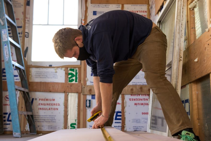 Preskenis measures a board inside the tiny house