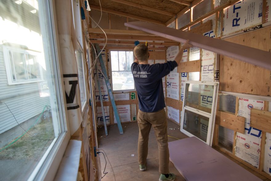 Preskenis lifts a piece of insulation to place inside the tiny house