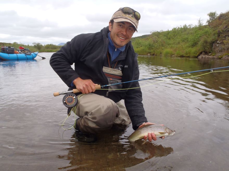 Tyler Dann holds a fish he caught while fly fishing 