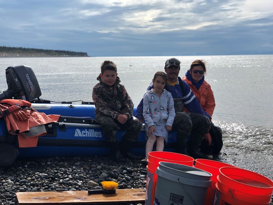 Tyler Dann and family sitting on a boat with mountains in the distance