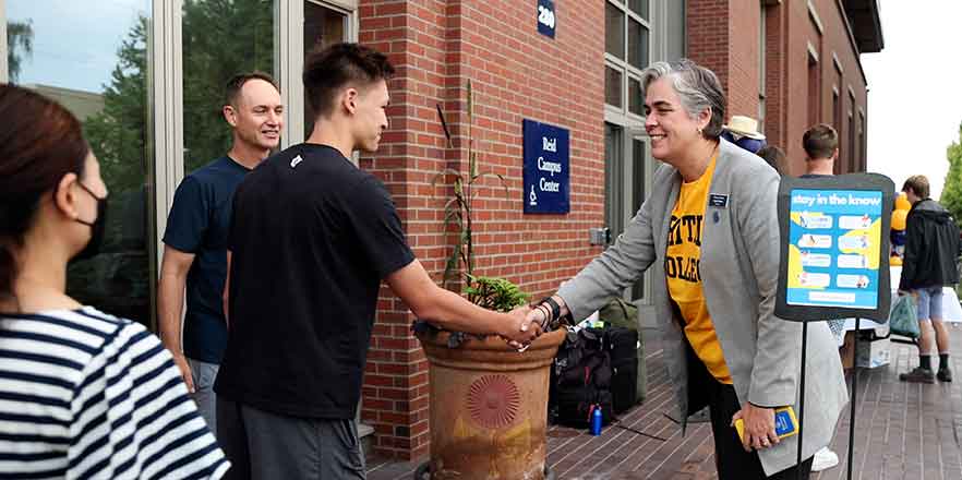 President Sarah Bolton shaking hands with a student.