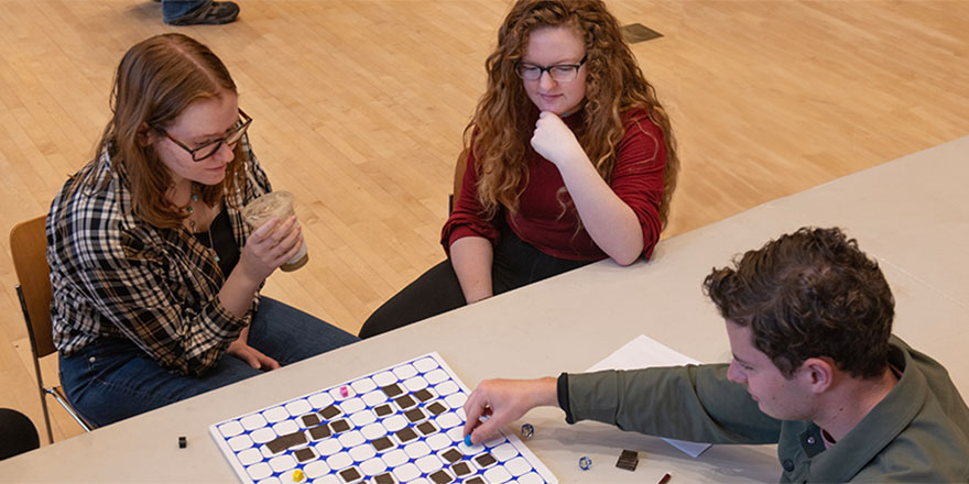 Three students playing a handmade board game.