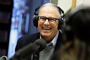 Governor Inslee, smiling, wearing over-the-ear headphones.