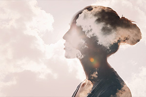 Abstract image of clouds superimposed over the silhouette of a woman.