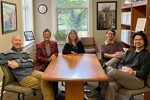 Five staff members sit around a table in an office setting. From left to right: Greg Lecki, Laura L. Cummings, Susan Holme, Nadir Ovcina, Ozzie Rodriguez.