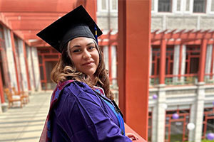 Salma Anguiano '22 smiling at the camera while posing in her graduation regalia in China.