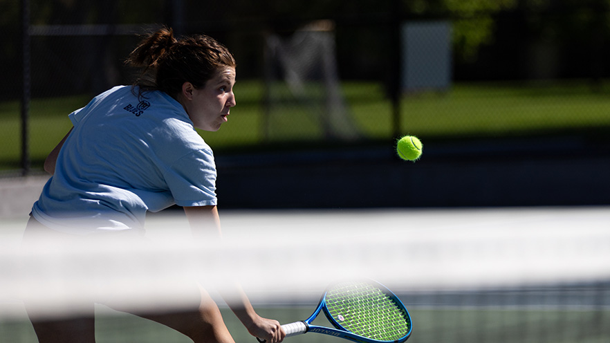 Sascha Wells returning the tennis ball with a volley.