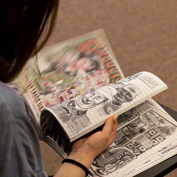 Whitman College student flipping through a graphic novel.