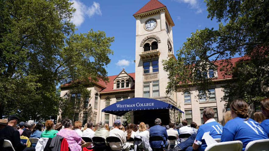 A crowd of people seated in front of Memorial Building at a commencement ceremony.